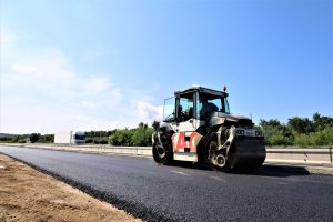 Pokládka první vrstvy asfaltového betonu pro podkladní vrstvu vozovky na dálnici D8. Foto: Strabag