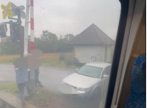 Lidé pomáhají zvednout závoru řidiči na přejezdu v Opatovci. Foto: Policie ČR